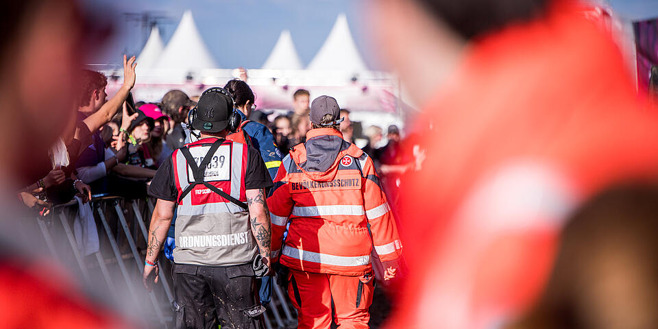 Sanitäter geht mit Security zu verletzter Person