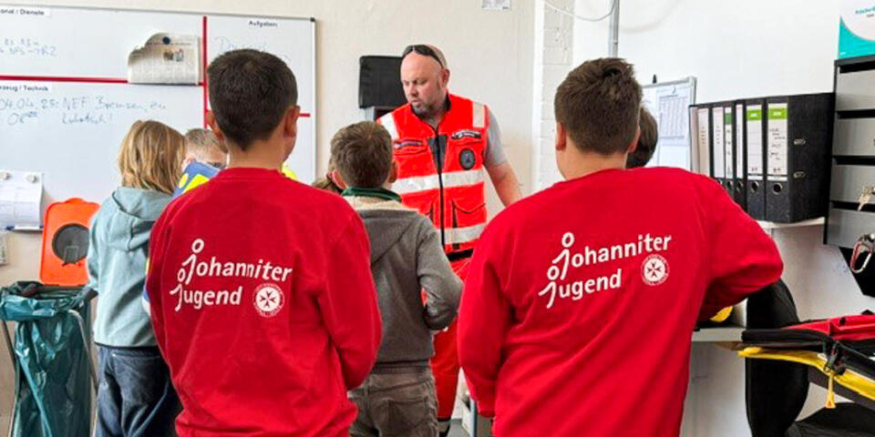 Kinder lauschen einem Rettungdienstmitarbeiter