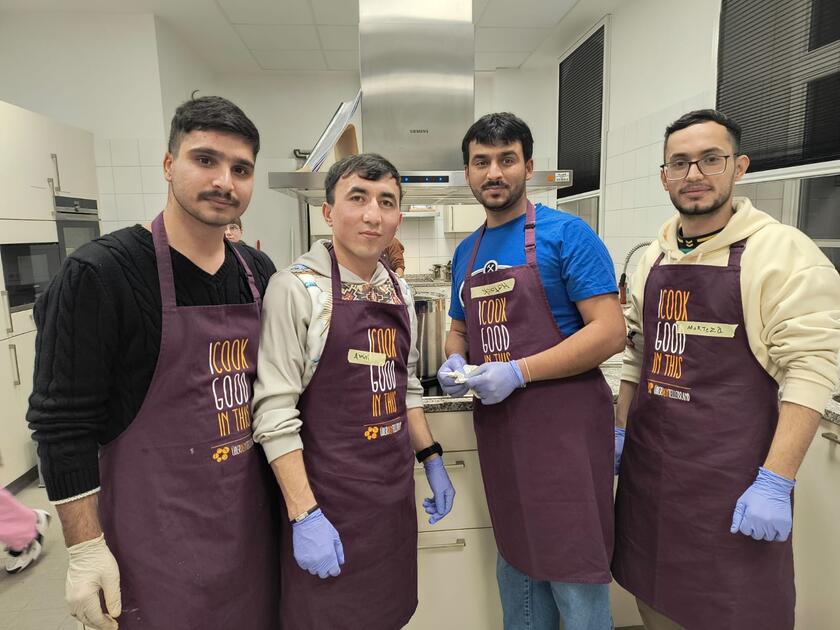 Vier Bewohnende der LUK mit Kochschürzen in der Küche