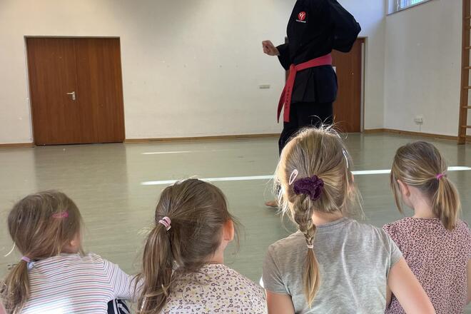 Kinder hören dem Sensei zu 
