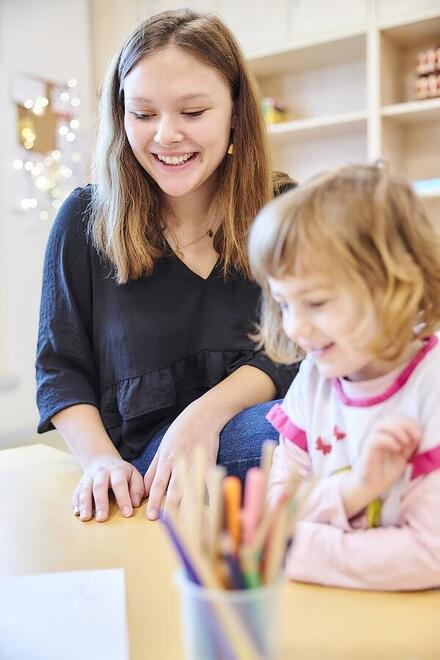Eine Auszubildende zur Erzieherin spielt mit einem Mädchen in einer Johanniter-Kita.