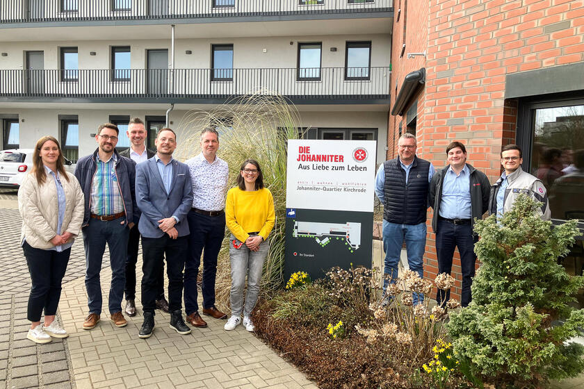 Zwei Frauen und sieben Männer vor einem Wohnkomplex