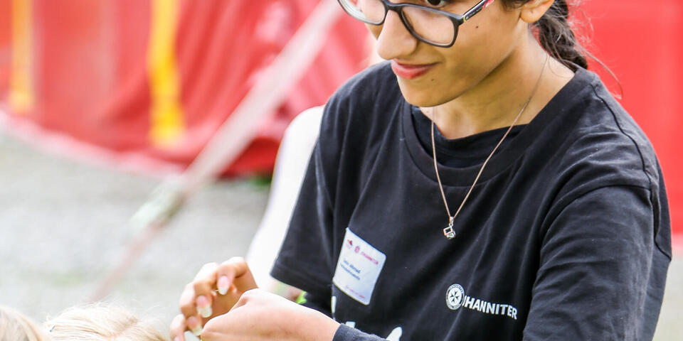Ferienbetreuerin stylt Haarband eines Kindes vor dem Auftritt.