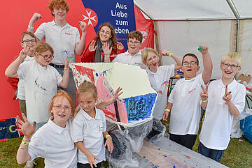 Eine Gruppe Kinder präsentiert gemeinsam ihre gestaltete Kreativarbeit.