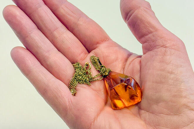 Ein Bernsteinanhänger, der in einer Handfläche liegt.