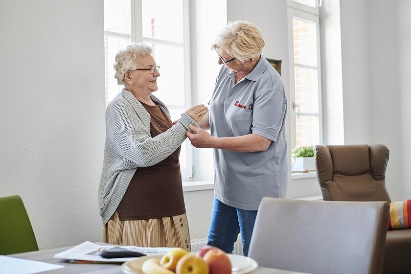 Eine Pflegekraft hilft einer älteren Frau beim Anziehen
