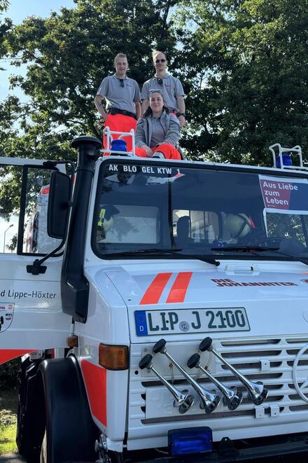 Zwei ehrenamtliche Helfende der Johanniter stehen auf dem Dach des Johanniter-Unimogs.