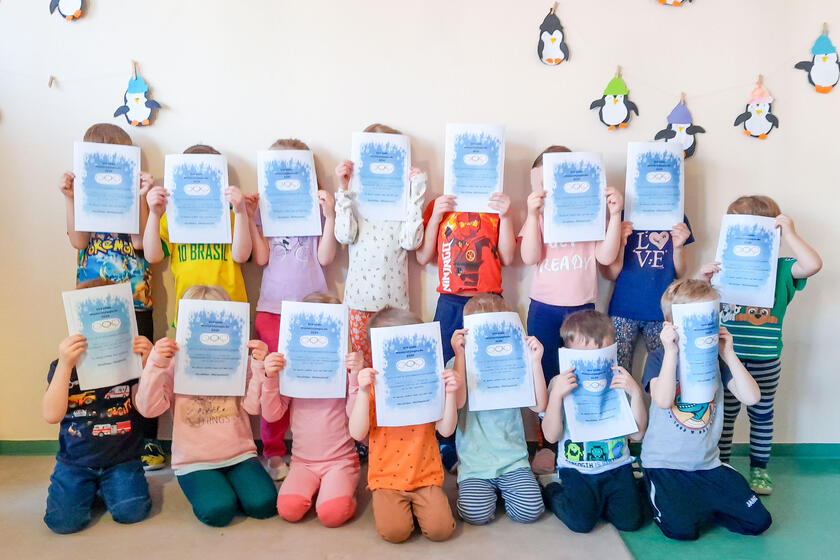 Die Kinder der Kita Gänseblümchen stehen für ein Gruppenfoto zusammen und halten sich die Urkunden vor das Gesicht.
