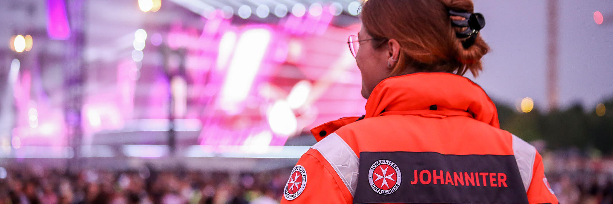 Eine Frau mit Johanniter Einsatzjacke auf einem Konzert sorgt für Erste-Hilfe im Sanitätsdienst.