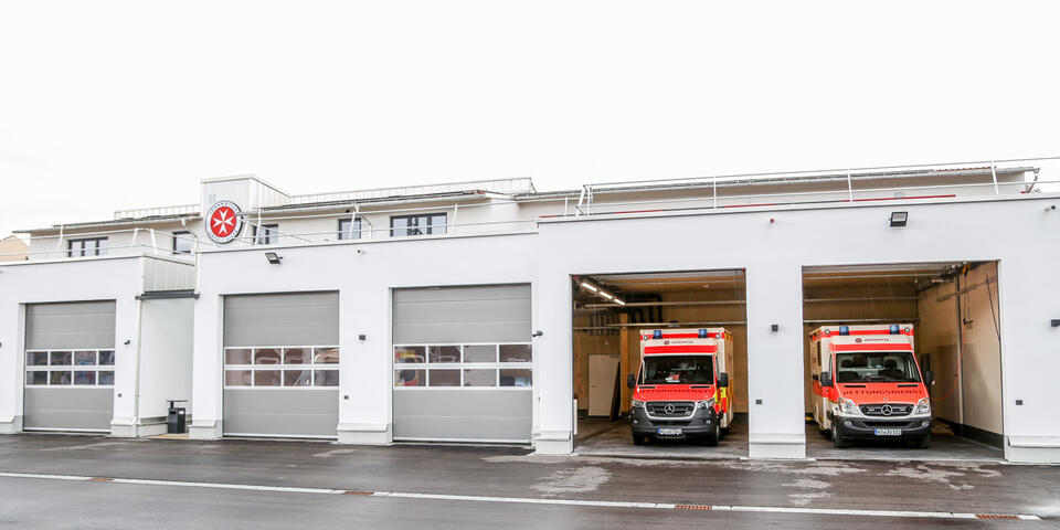 Neue Johanniter-Zentrum mit zwei geöffneten Garagen und Einsatzfahrzeugen.