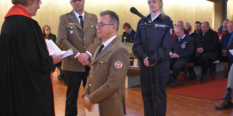 Ortsbeauftragter Peter Galdia kniet vor Landespfarrerin Inge Matern bei der Einsegnung.