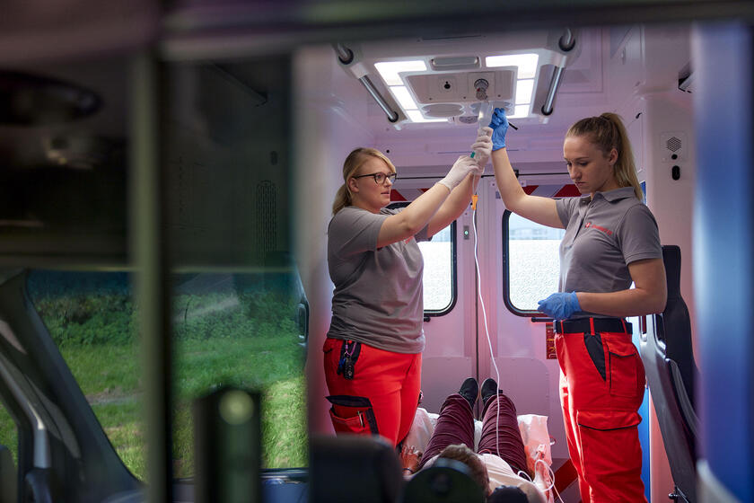 Zwei Notfallsanitäterinnen der Johanniter versorgen eine Patientin in einem Rettungswagen mit einer Infusion.