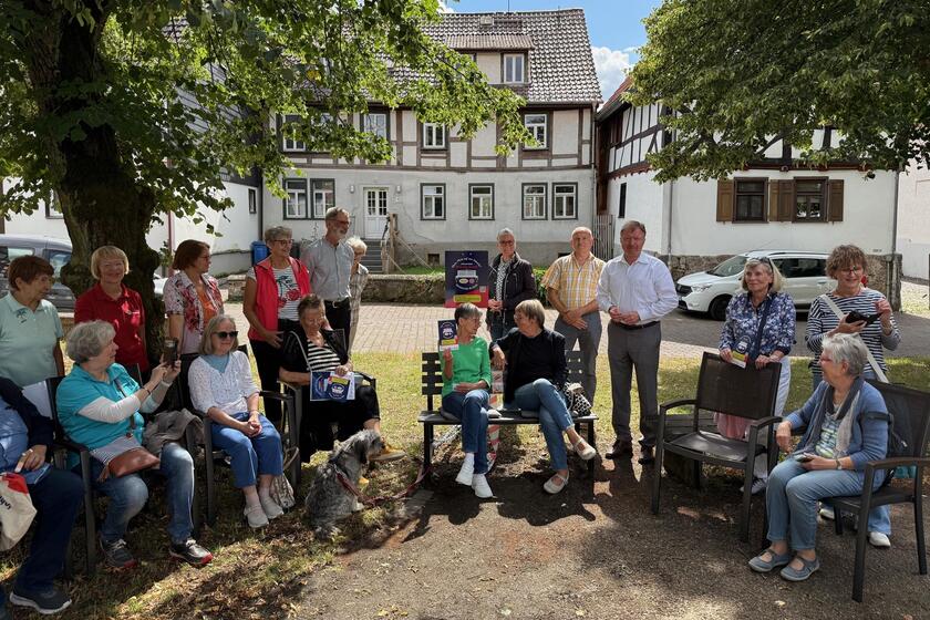 Viele Manschen als Gruppenfoto um Plaudertbank herum