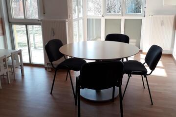In einem kleineren Raum steht ein runder Tisch mit vier Stühlen für individuelle Beratungen.