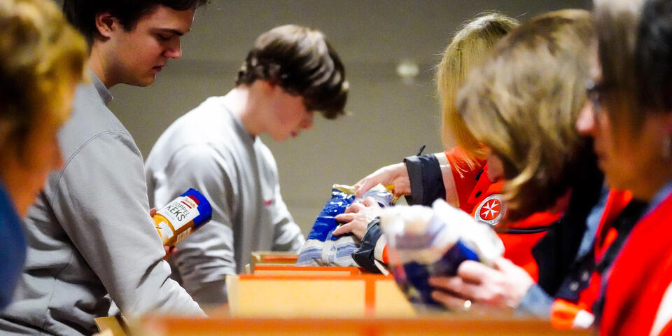 Frauen und Männer in Johanniter-Kleidung packen Lebensmittel in Pakete