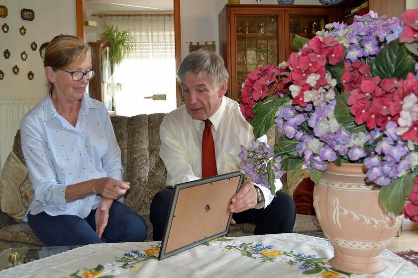 Eine Mitarbeiterin und ein Mann sprechen über seine verstorbene Mutter und zeigen auf ihr Foto.