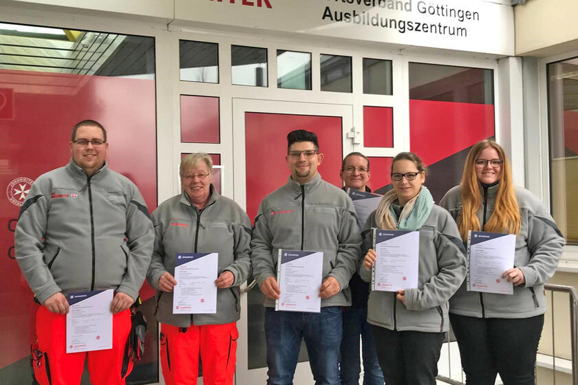 Vier Frauen und zwei Männer mit Zertifikaten vor dem Eingang des Campus Göttingen