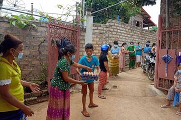 Eine Menschenkette die Eier weiterreicht. Alle tragen Masken und halten Abstand.