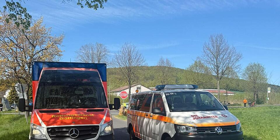 Ein Rettungswagen und ein Mannschaftstransportwagen stehen auf einer Landstraße.