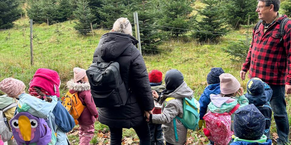 Eine Frau, ein Mann und eine Schar von Kindern schauen auf einen Wald.