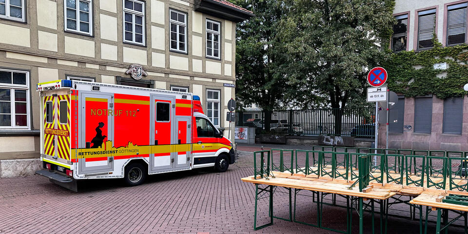 Ein Rettungswagen auf einem Kirchenvorplatz. Im Vordergrund sind Bierzeltgarnituren