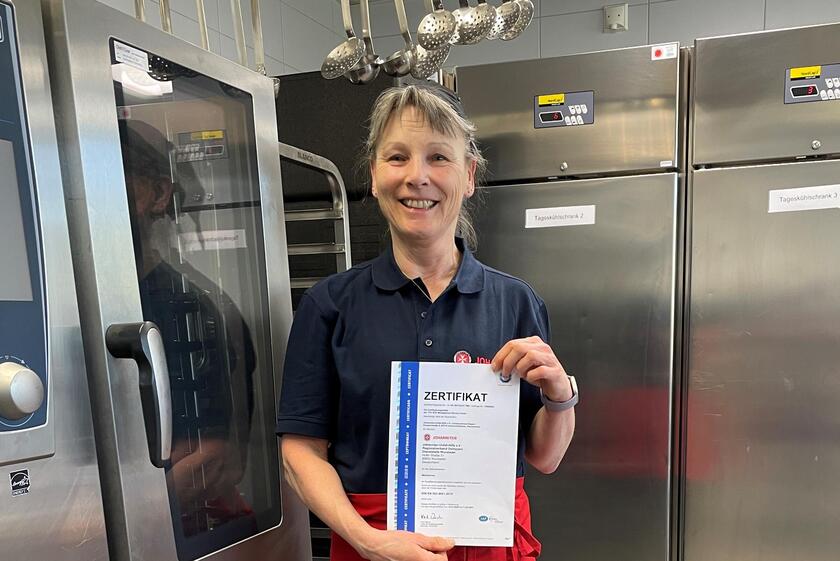 Frau hält TÜV-Zertifikat hoch