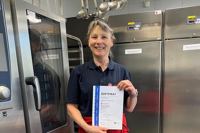 Frau hält TÜV-Zertifikat hoch