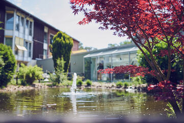Über einen kleinen Gartenteich schaut man auf das Johanniterhaus Celle