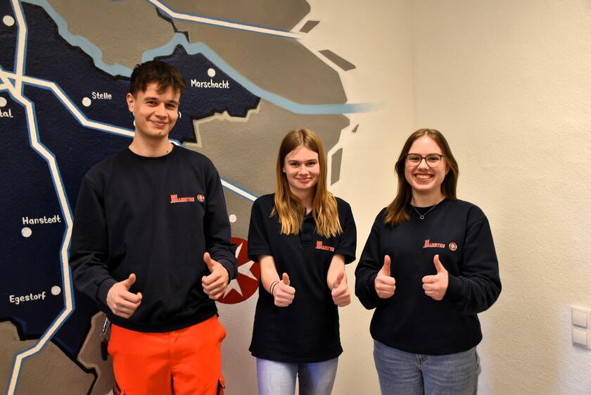 drei junge Menschen, die Freiwilligendienst bei den Johannitern leisten, strecken die Daumen nach oben
