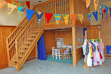 Spielecke mit Puppen, einer kleiner Spielküche und Kostümen um sich zu Verkleiden.