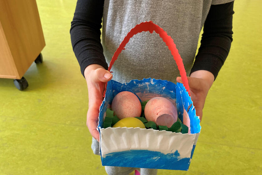 Kinderhände halten ein Körbchen mit Ostereiern
