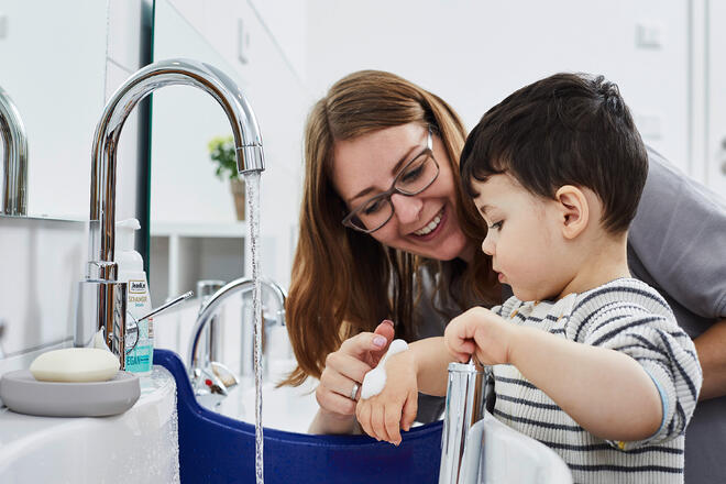 Eine Johanniter-Erzieherin beschäftigt ein Kita-Kind am Waschbecken.