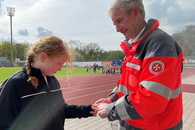 Wilfried Remy, ehrenamtlicher Helfer bei den Johannitern, versorgt eine Grundschülerin. 