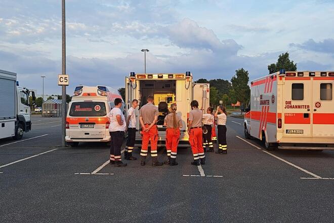 Eine Gruppe von Mitgliedern der Johanniter-Jugend steht vor einem Rettungswagen auf einem Parkplatz