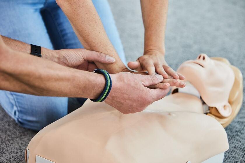 Eine Kursteilnehmerin übt die Reanimation und richtige Haltung der Hände an einer Übungspuppe.