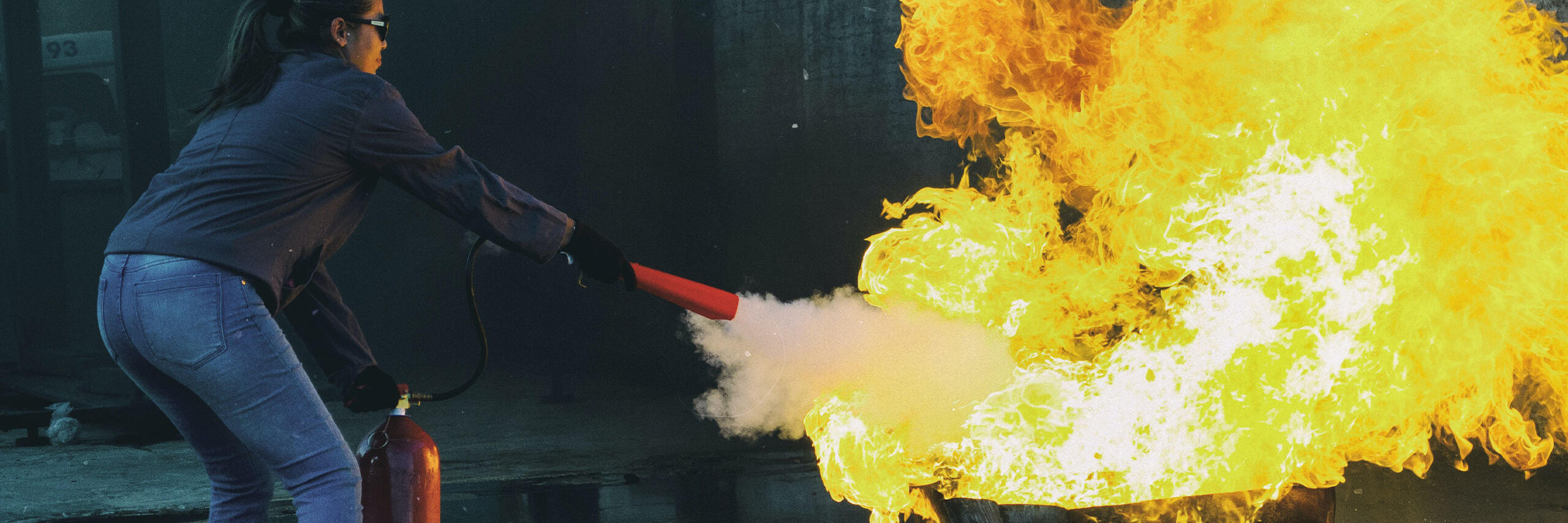 Eine Person löscht ein großes Feuer mit einem Feuerlöscher, wie es Teilnehmende des Kurses Brandschutzhelfer bei den Johannitern in Wiesbaden tun.