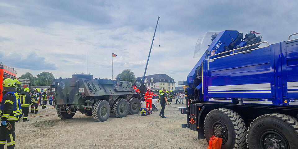 Ein Truppentransportpanzer, ein THW-Fahrzeug mit Leiter und Einsatzkräfte von den Johannitern und der Feuerwahr auf einem Platz