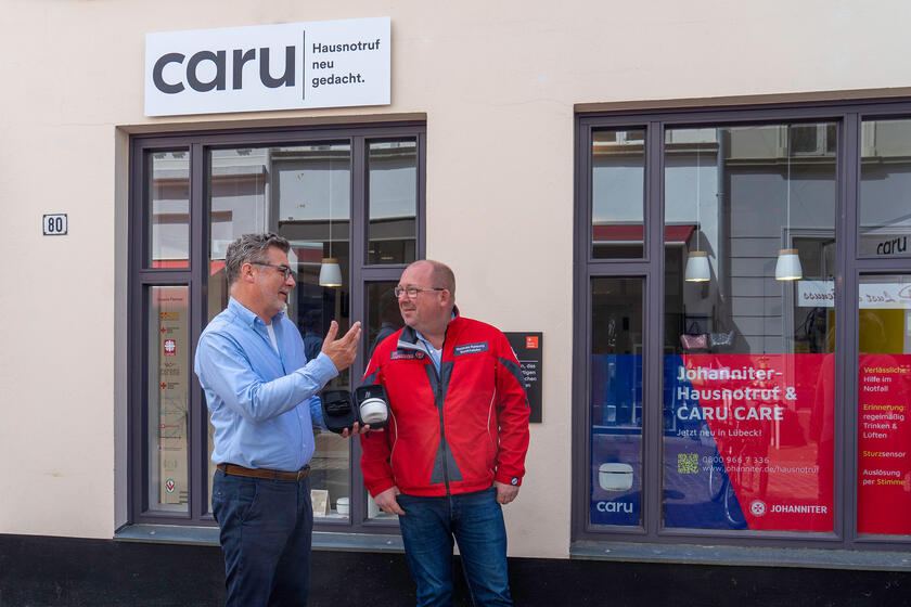 Bernd Jacobi (CARU GmbH) und Matthias Rehberg (Johanniter-Unfall-Hilfe e.V.) blicken positiv auf die Kooperation im Bereich Hausnotruf. Das Schweizer Unternehmen hat ein Ladengeschäft in der Hüxstraße 80 in Lübeck und berät dort Interessierte. Bei den Johannitern können Kundinnen und Kunden in Schleswig-Holstein Süd/Ost das Gerät direkt online oder über die Hotline bestellen.