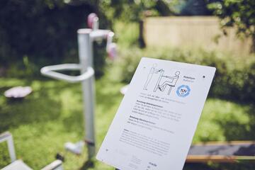 Erklärschild und Sportgerät im Garten