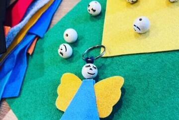 Ein kleiner Filzengel, der gerade gebastelt wird und auf einigen Bastelmaterialien liegt 