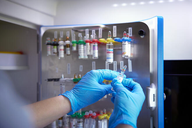 Eine Ampulle wird aus einem Schrank für Notfallmedikamente entnommen.