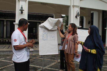 Sariyah und weitere Mitarbeitende vor einem beschriebenen Clipboard