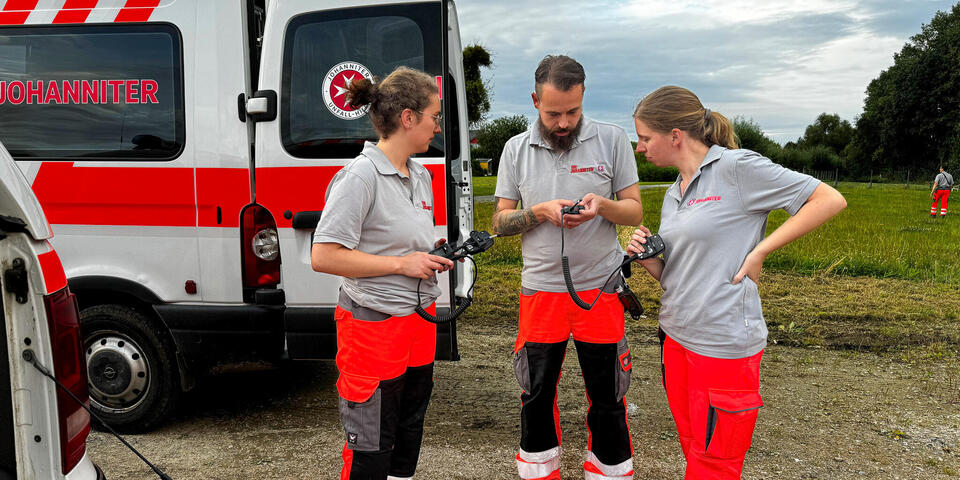 Drei Mitglieder der Rettungshundestaffel schauen auf ein Tablet