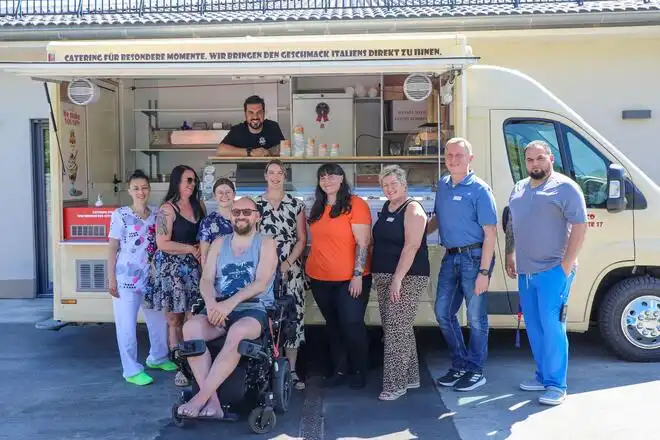 Mitarbeitende und ein Hospiz-Gast freuen sich über den Besuch des Eiswagens