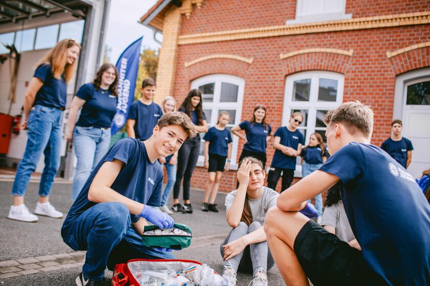 Johanniter-Jugend im Hof bei der Übung, Flagge und RTW im Hintergrund