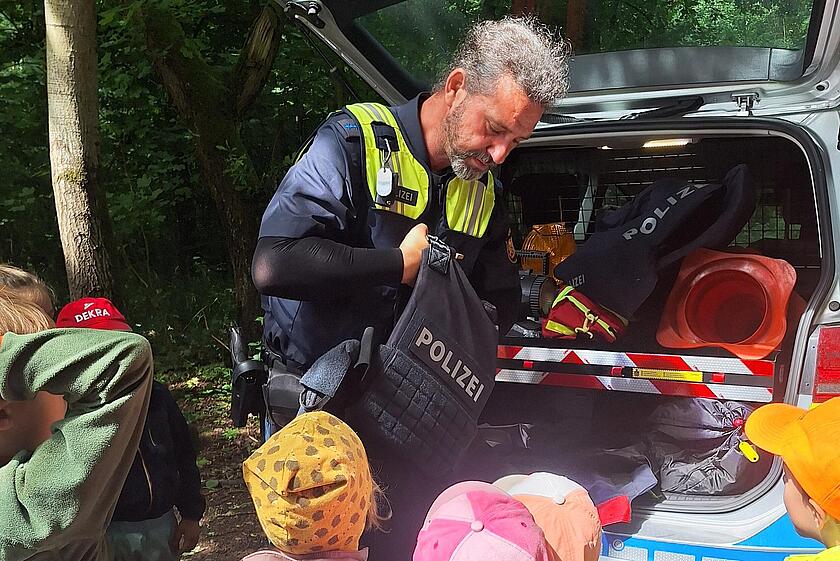 Die Kinder blicken gespannt auf die Ausrüstung der Polizei.