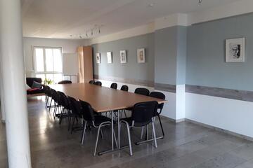 In einem großen Raum stehen Tische und Stühle.