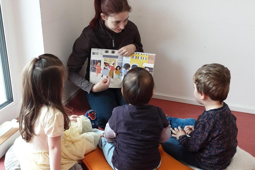 Die Kinder hören der Erzieherin gespannt beim vorlesen eines Buches zu