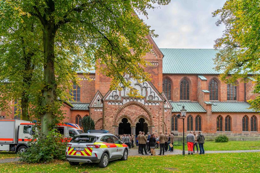 Vor dem Dom zu Lübeck stehen Fahrzeuge der Johanniter sowie viele Menschen, die den Festgottesdienst besuchen.