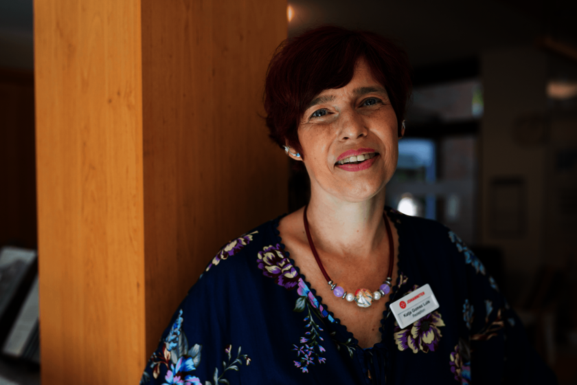 Eine Frau mit rotem Haar lehnt an einer Holzsäule im Innenraum